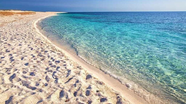 A beach with clear water, sandy shore, and a clear sky. - Club Malaspina Hotel & Resort (Bosa)