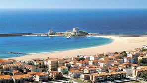 A coastal town with a beach, a fortified structure, and densely packed buildings with red-tiled roofs. - Club Malaspina Hotel & Resort (Bosa)