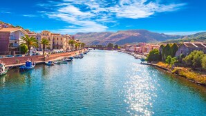 A river with boats, buildings along the banks, and mountains in the background. - Club Malaspina Hotel & Resort (Bosa)