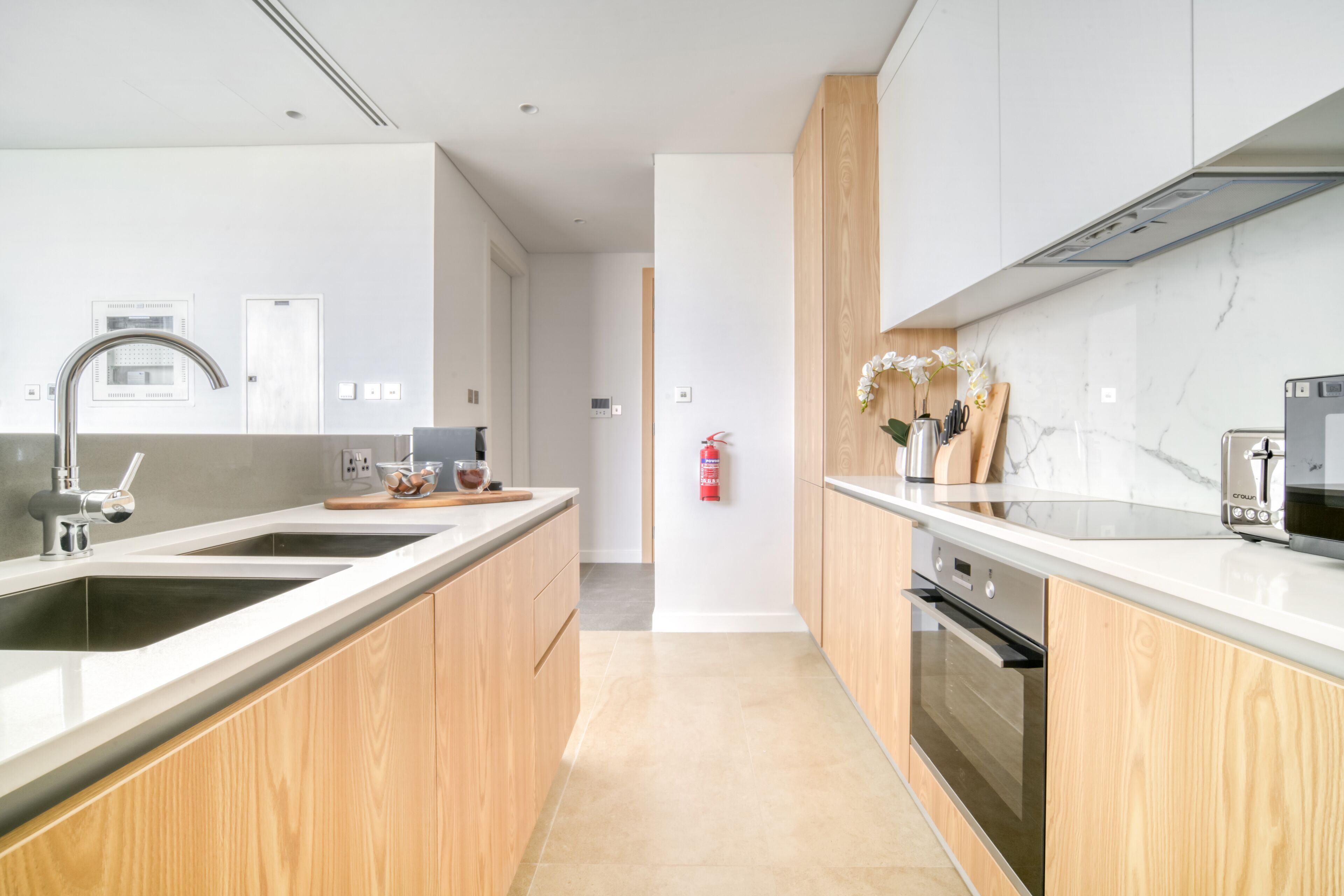 A modern kitchen with wooden cabinets, stainless steel appliances, and a marble countertop.