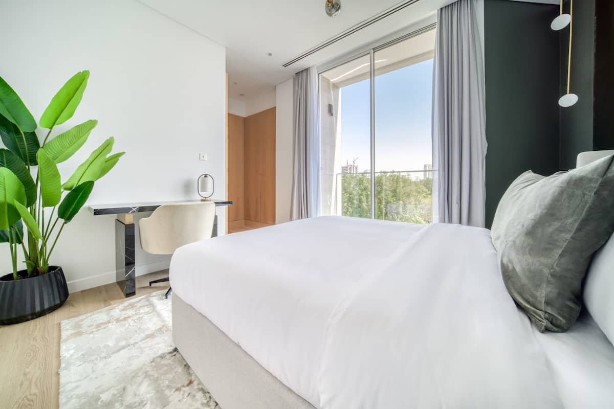 Un dormitorio moderno con una cama grande, un escritorio y una planta en maceta.