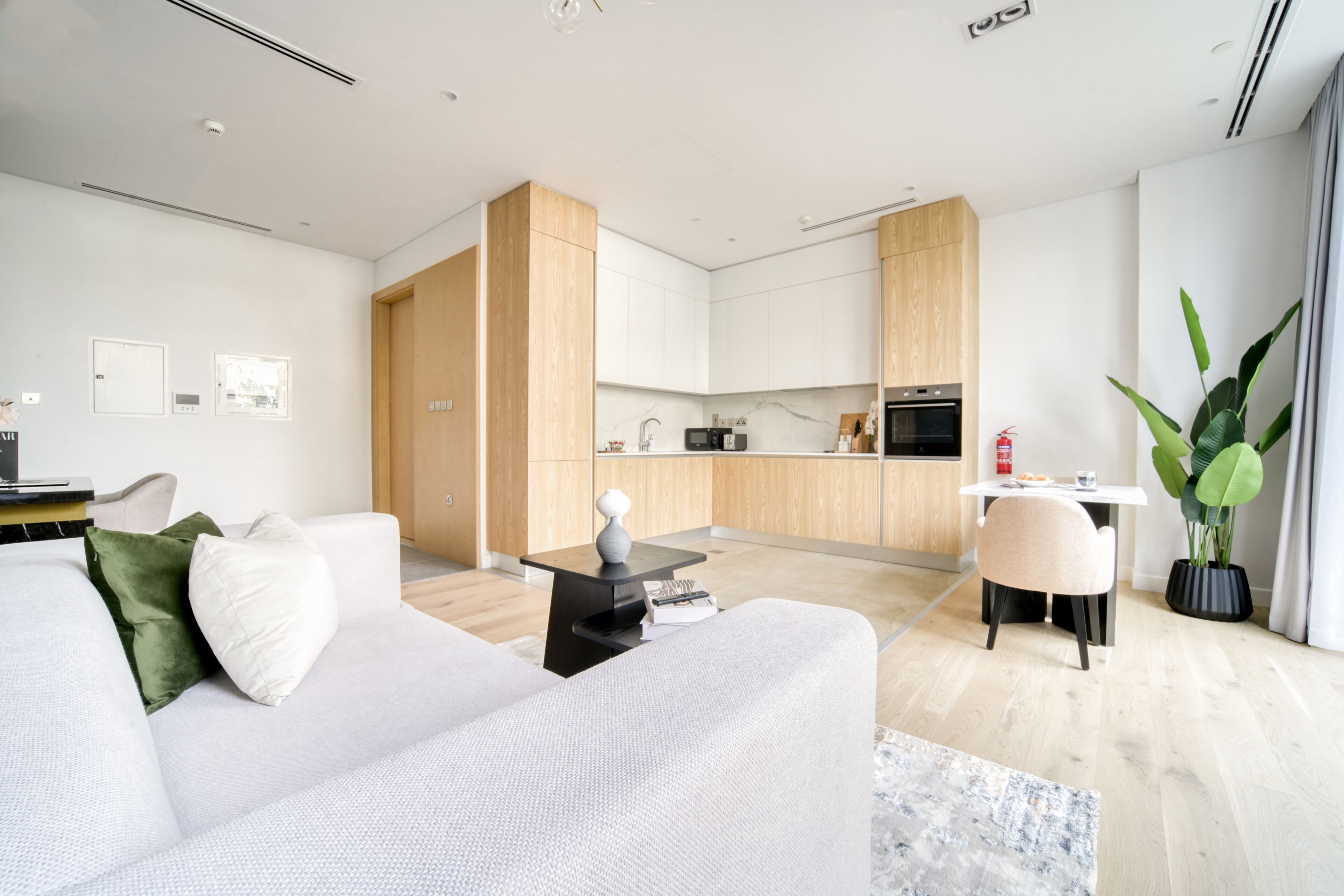 A modern living room with a white sofa, a coffee table, and a dining area with a table and chairs.