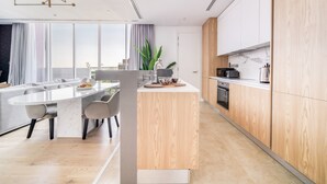 A modern kitchen with a central island, wooden cabinets, and a large window providing natural light. - Al Barari Stella Stays (Dubai)