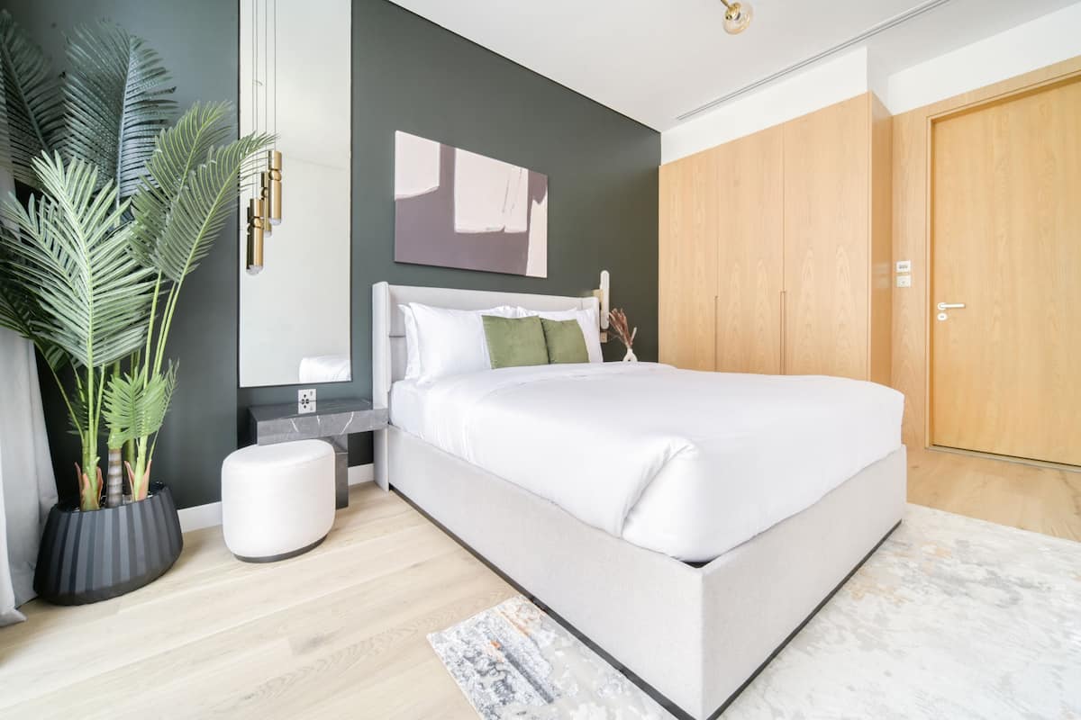 Un dormitorio moderno con una cama grande, una mesita de noche, una planta en maceta y un armario de madera.