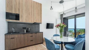 Una cocina moderna con armarios de madera, horno empotrado y zona de comedor con mesa redonda y sillas azules.