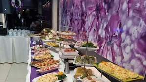 A buffet table with various food items and a purple wall in the background. - Villa Solaris (Rewal)