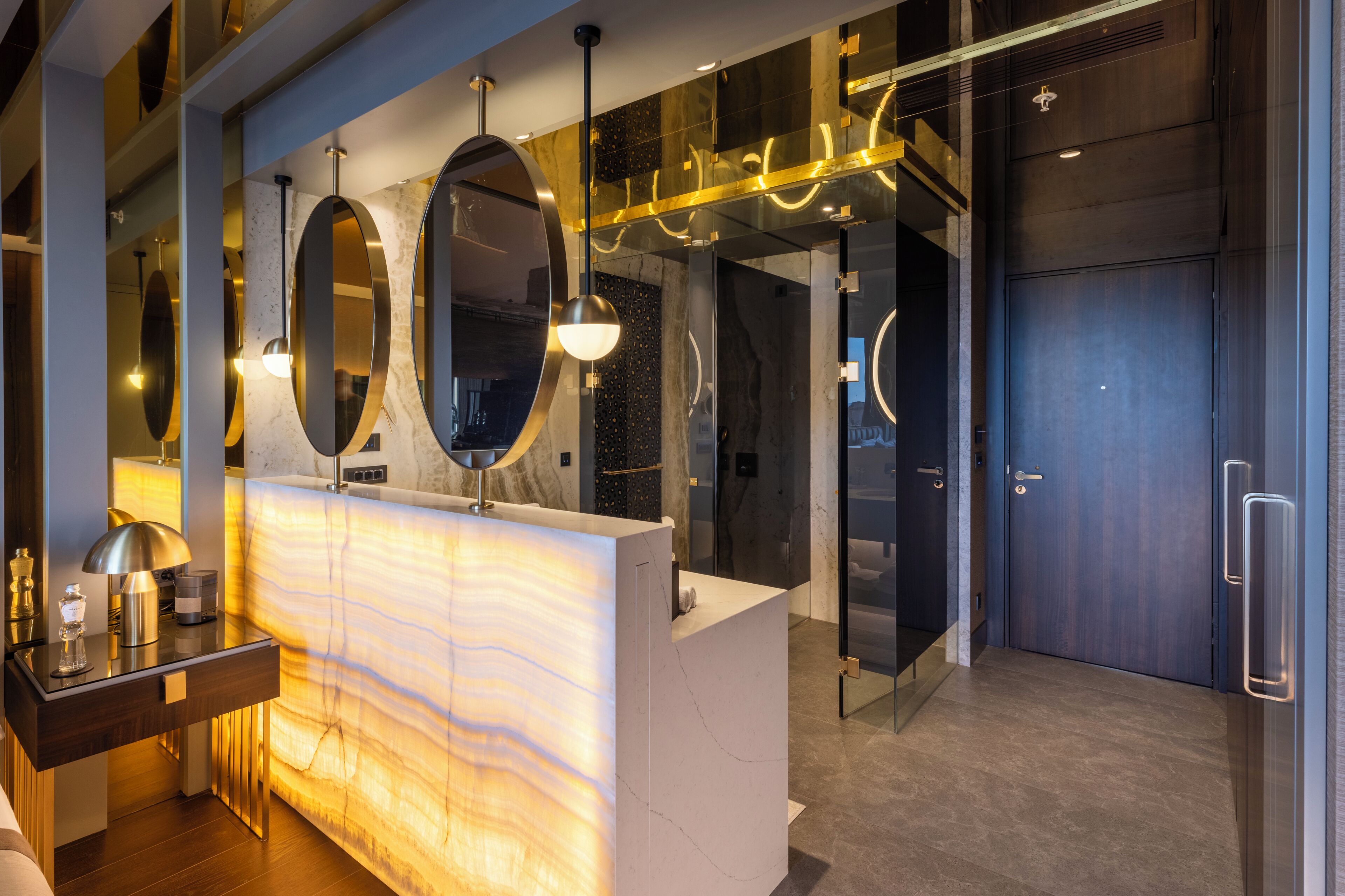 A modern bathroom with a marble vanity, large mirrors, and a glass shower enclosure.
