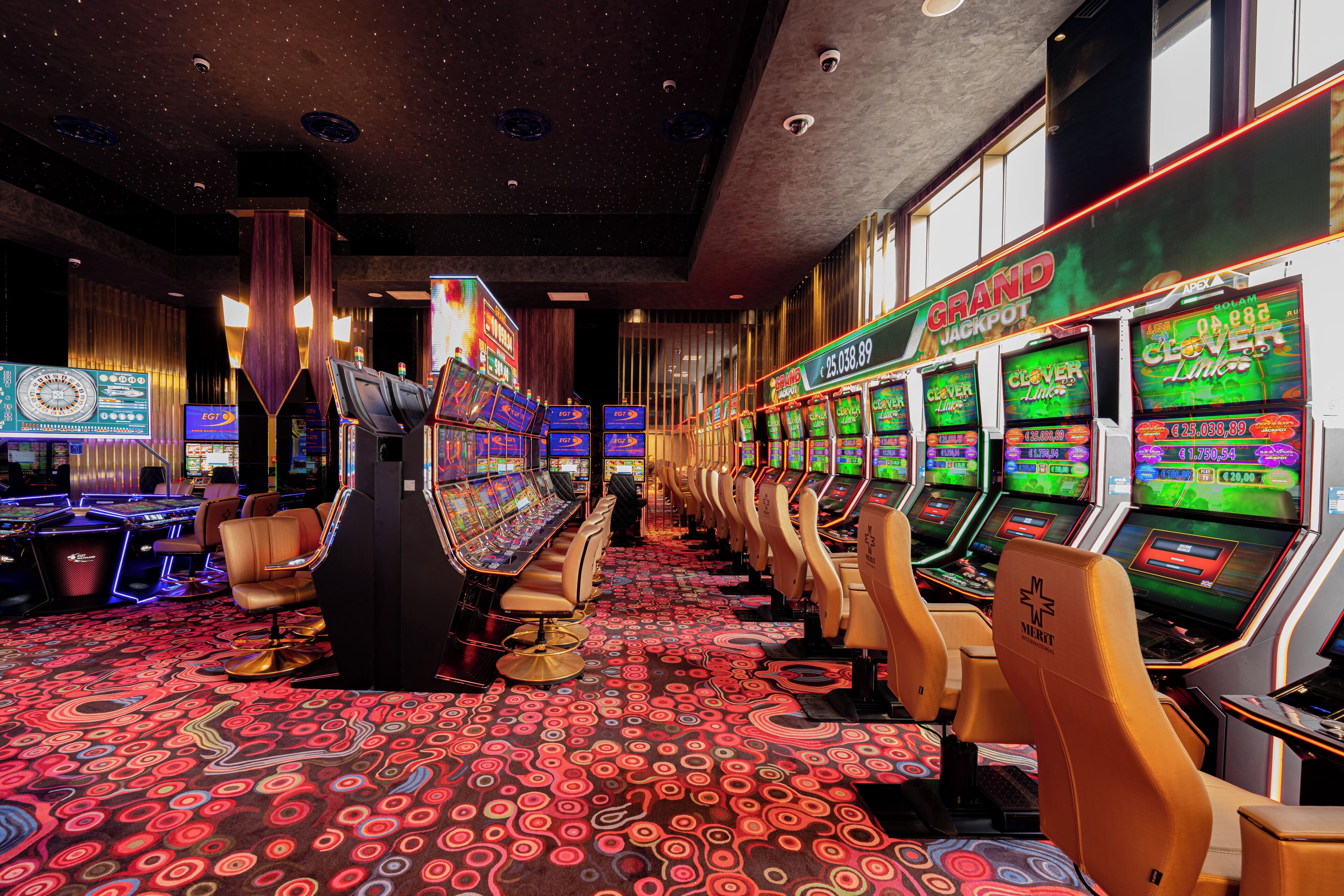 A casino with multiple slot machines and a carpeted floor.