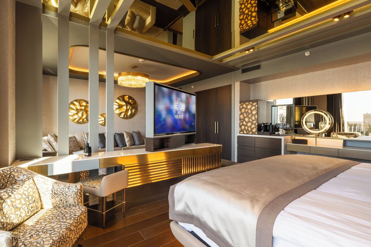 Une chambre d’hôtel moderne dotée d’un grand lit, d’un coin salon avec télévision et d’une kitchenette.