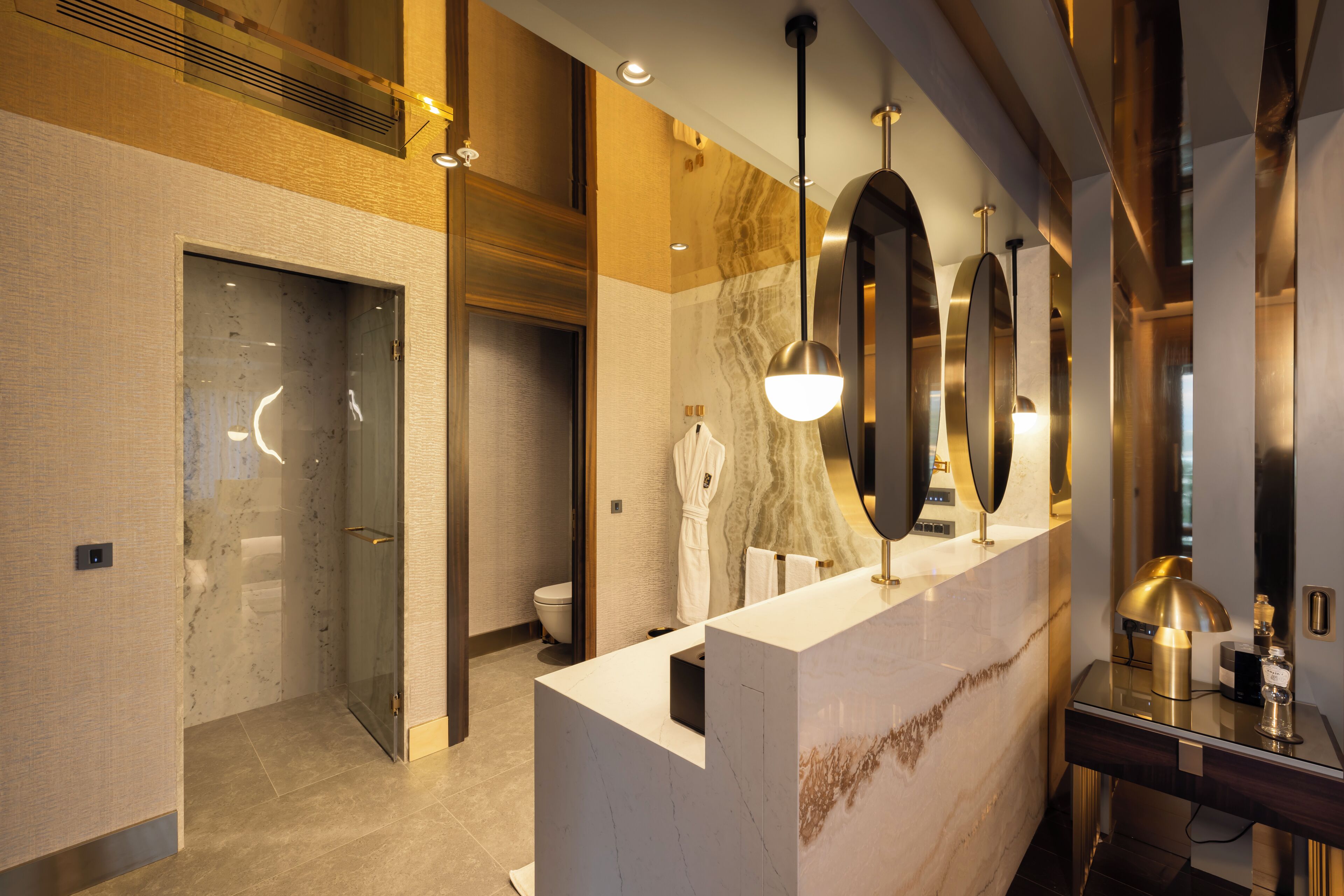 Une salle de bain moderne avec un meuble-lavabo en marbre, une cabine de douche en verre et un grand miroir.