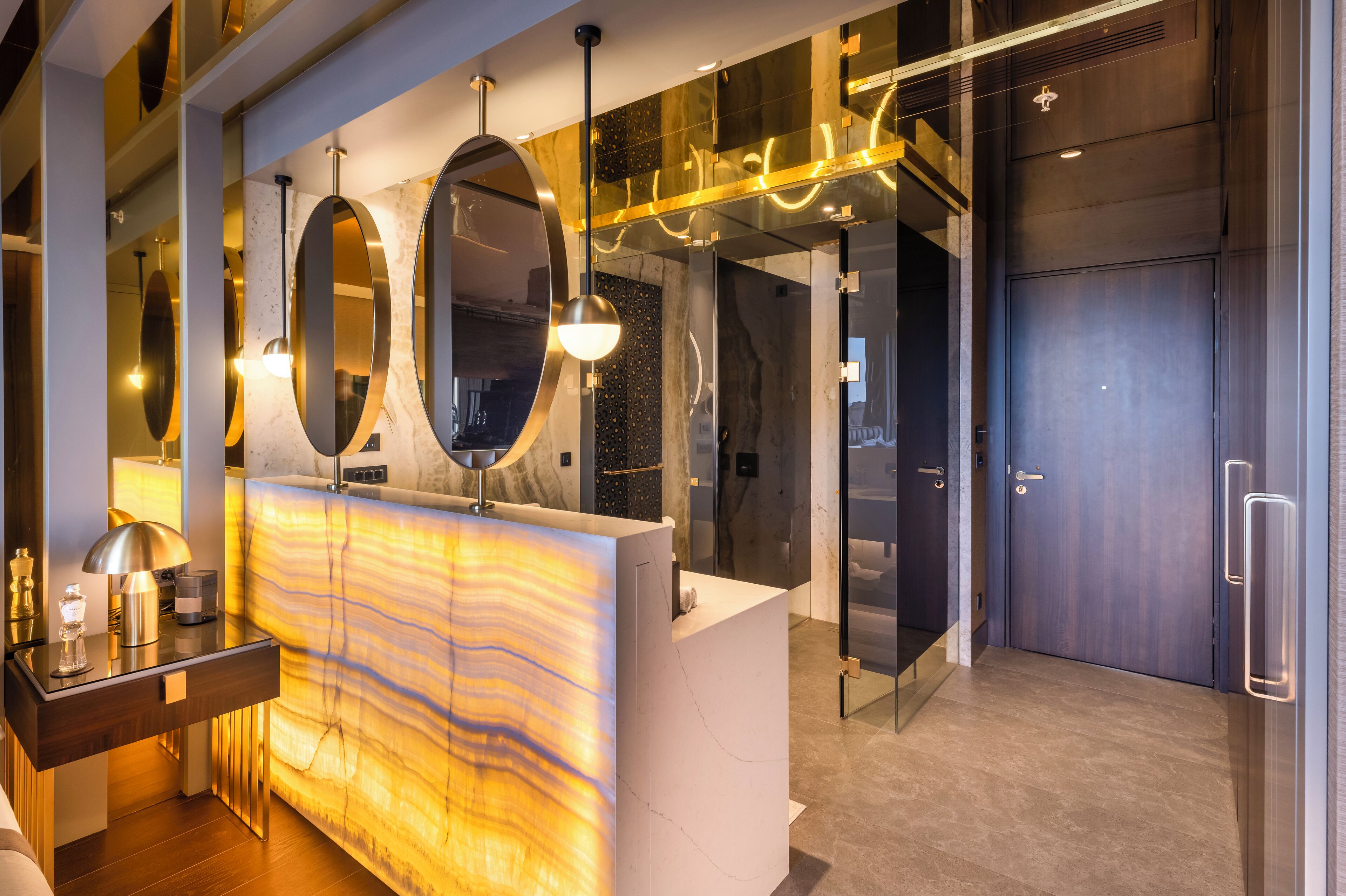 A modern reception area with a marble counter, large mirrors, and contemporary lighting fixtures.
