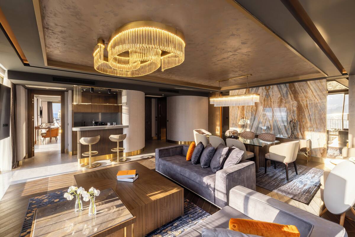 Un salon moderne doté d’un grand canapé, d’une table basse et d’un coin repas avec un mur en marbre et un lustre.