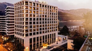 A multi-story hotel with a prominent "MDRIFTY" sign, featuring a modern architectural design with a central courtyard and a view of the surrounding landscape. - Merit Starlit Hotel Casino & SPA (Budva)