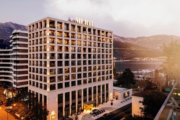 A multi-story hotel with a prominent "MDRIFTY" sign, featuring a modern architectural design with a central courtyard and a view of the surrounding landscape. - Merit Starlit Hotel Casino & SPA (Budva)