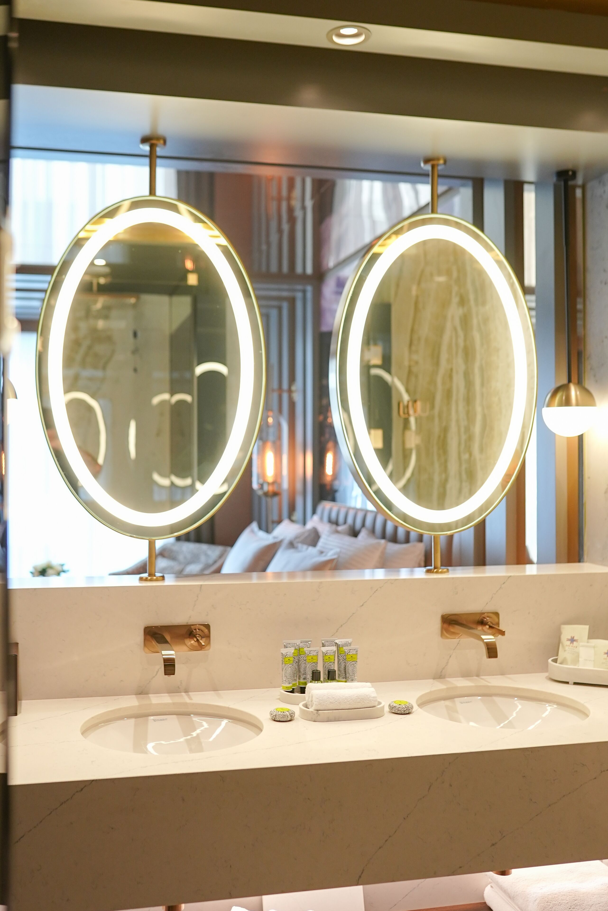 A bathroom with two round mirrors, a sink, and a vanity.