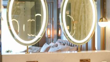 A bathroom with two round mirrors, a sink, and a vanity.