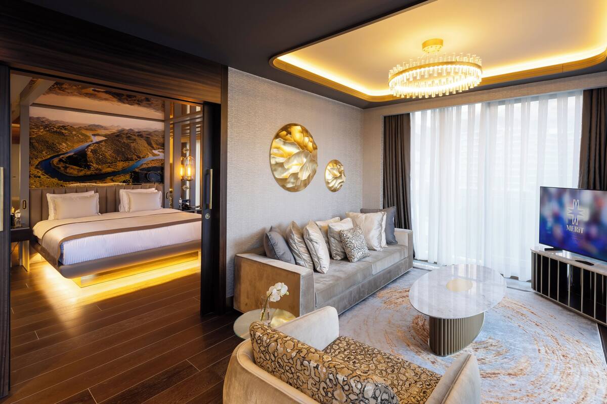 Une chambre d’hôtel moderne équipée d’un lit, d’un canapé, d’une télévision et d’une grande fenêtre avec des rideaux.
