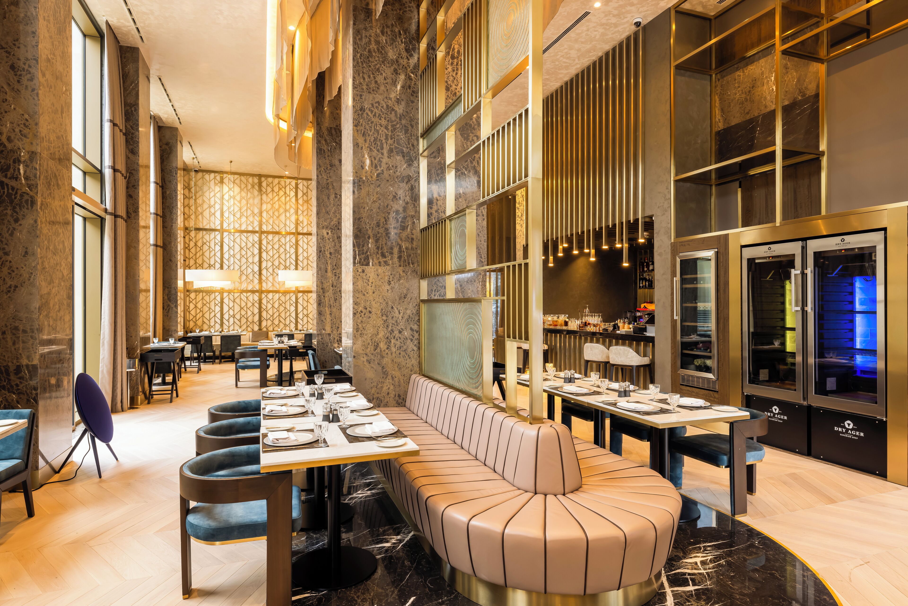 En moderne restaurant med et langt fællesskabslaug, polstrede siddepladser og et barområde.