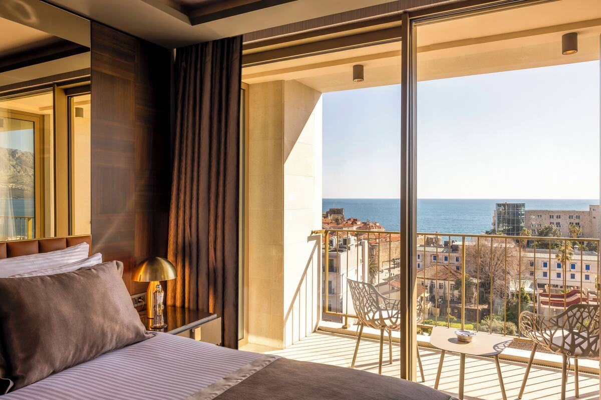 Une chambre d’hôtel avec un grand balcon, un lit, une table et des chaises.
