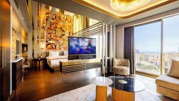Una sala de estar moderna con un televisor de pantalla plana grande, un sofá, una mesa de centro y vistas a la ciudad a través de amplias ventanas.