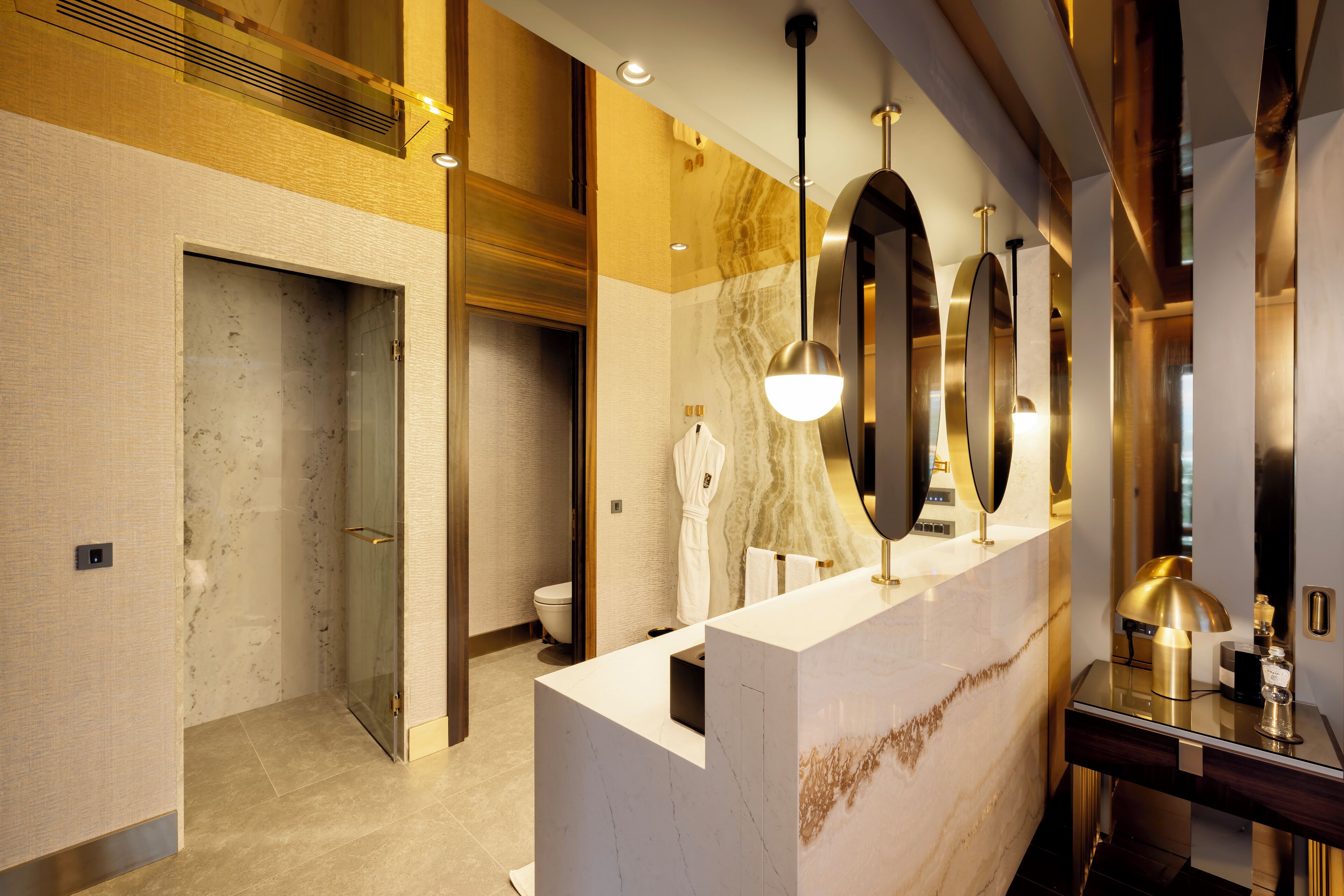 A modern bathroom with a marble vanity, a glass shower enclosure, and a large mirror.