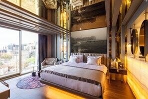 A modern hotel room with a large bed, a city view, a round mirror, and a desk with a lamp. - Merit Starlit Hotel Casino & SPA (Budva)