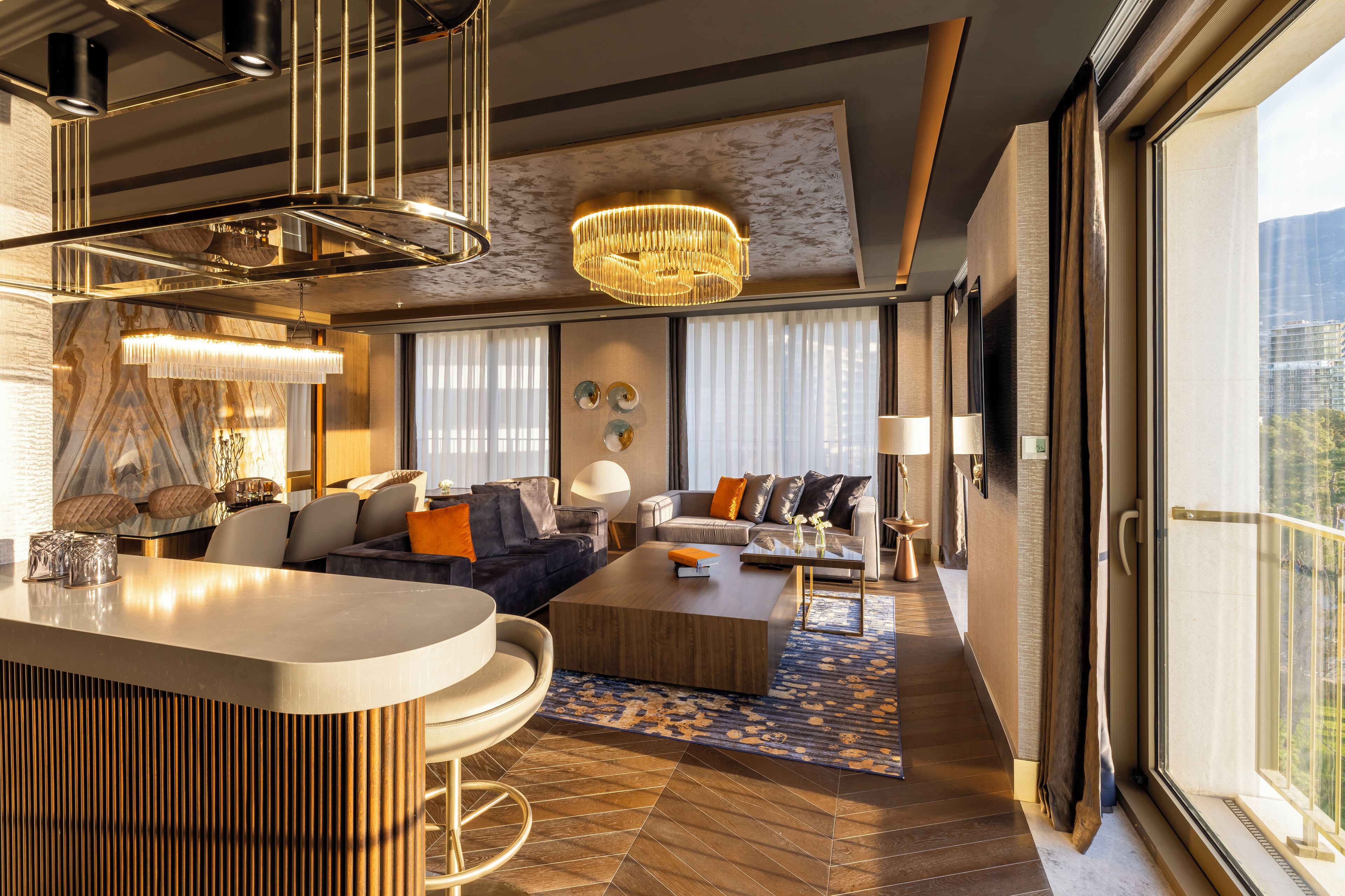 Un salon moderne doté d’un coin bar, de grandes fenêtres et d’un lustre.