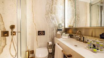A modern bathroom with a glass-enclosed shower, a toilet, and a vanity with a large mirror.