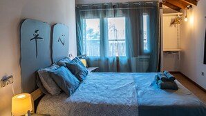 Un dormitorio con cama, mesita de noche, lámpara, ventana con cortinas y techo de madera.