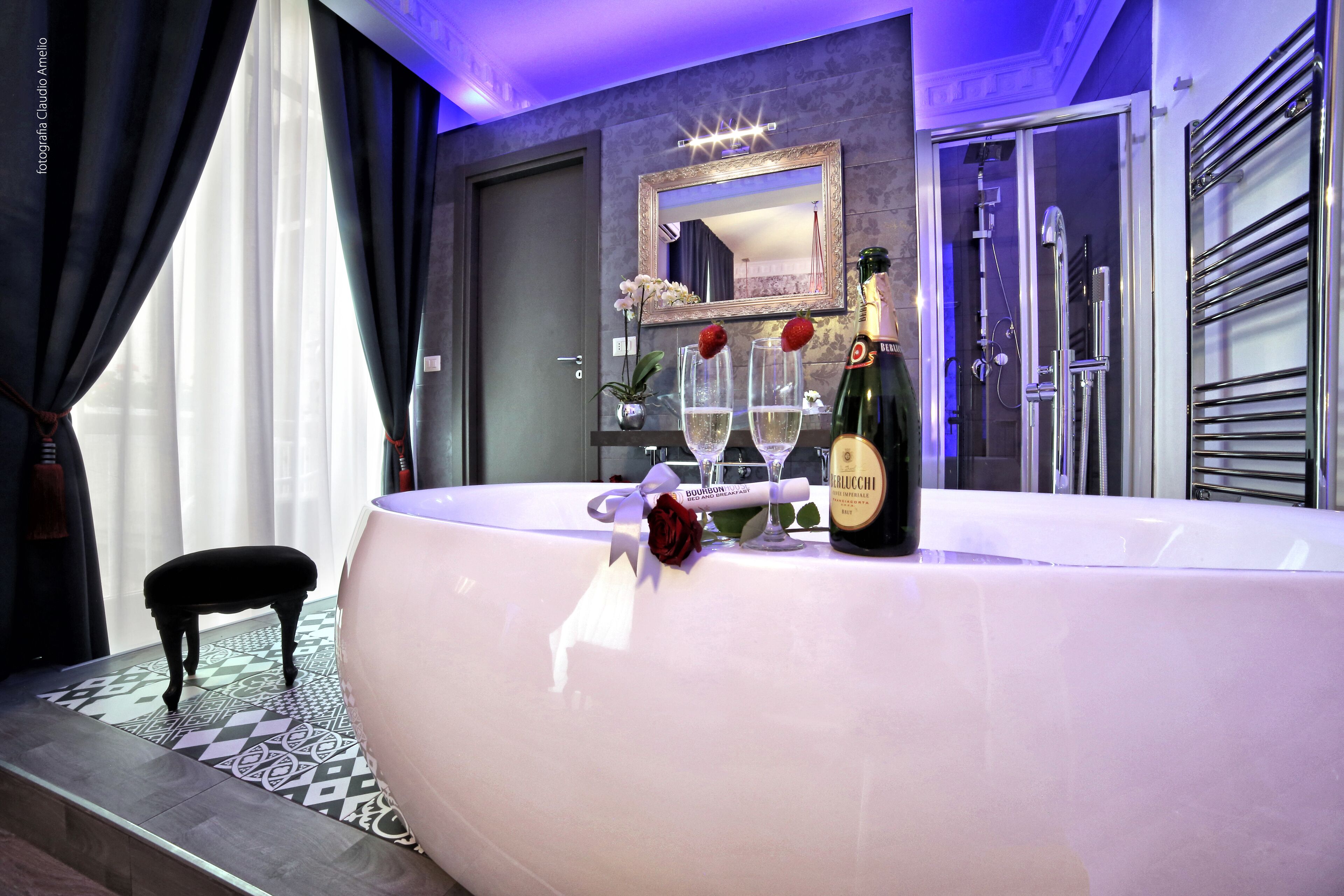 Une salle de bain moderne avec une grande baignoire, un meuble-lavabo avec un miroir et une bouteille de champagne.