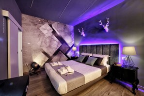 A modern bedroom with a large bed, a headboard, a nightstand, and a wall-mounted deer head decoration. - Bourbon House (Naples)