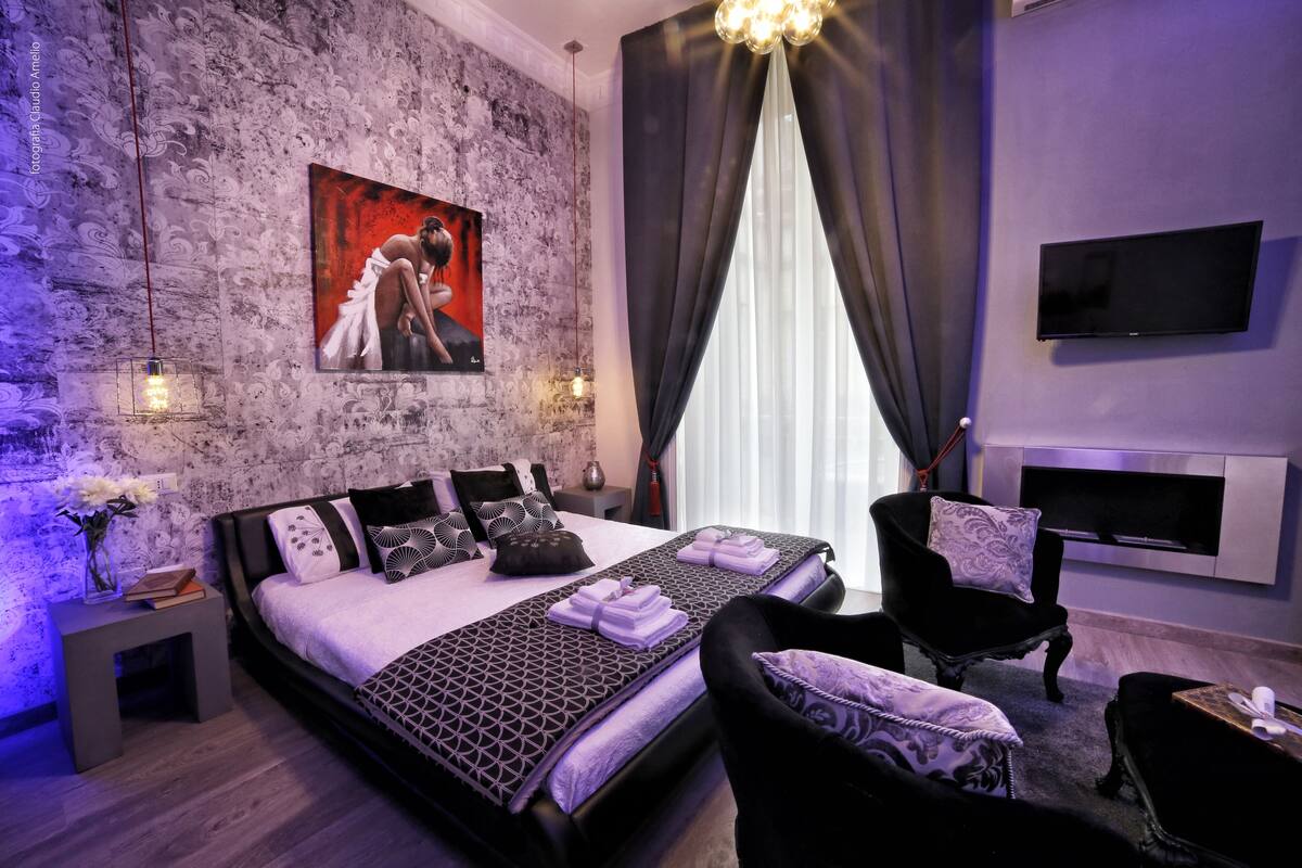 Une chambre moderne avec un grand lit, un téléviseur à écran plat et une cheminée.