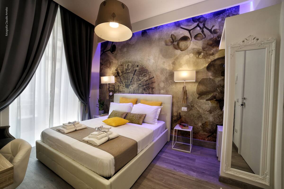 Une chambre moderne avec un grand lit, des lampes de chevet, une fresque murale décorative et une armoire.