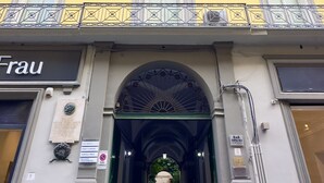A building facade with a yellow exterior, a sign reading "Frau," and an arched entrance. - Bourbon House (Naples)