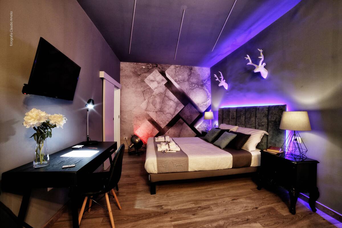 Une chambre à coucher moderne, comprenant un lit, une table de chevet, une lampe et un bureau avec une chaise.
