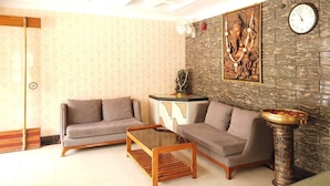 Un soggiorno con due divani, un tavolino, un comodino, una sveglia e un elemento decorativo a parete.