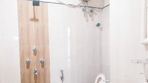 Un bagno con porta in legno, un water, un lavandino e una doccia.