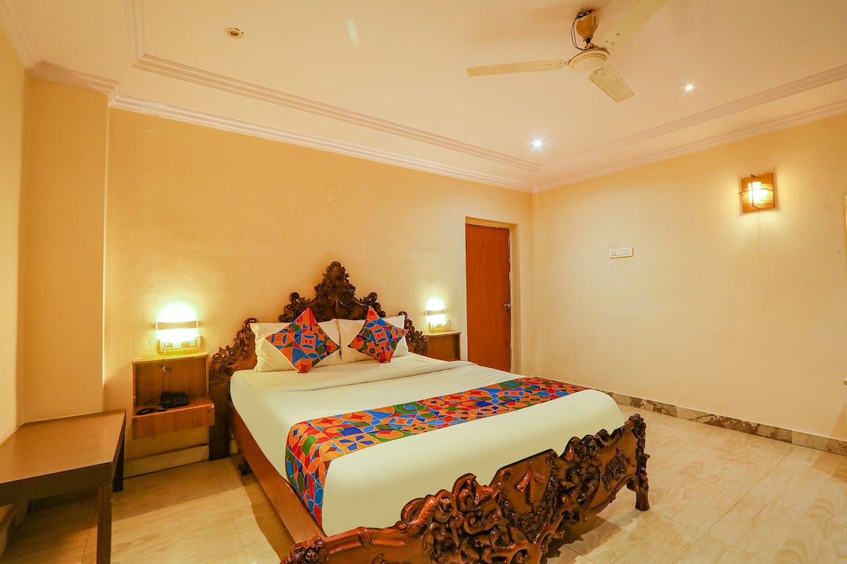 Quarto com uma cama grande, cabeceira de madeira, duas mesas de cabeceira com luminárias e um ventilador de teto.