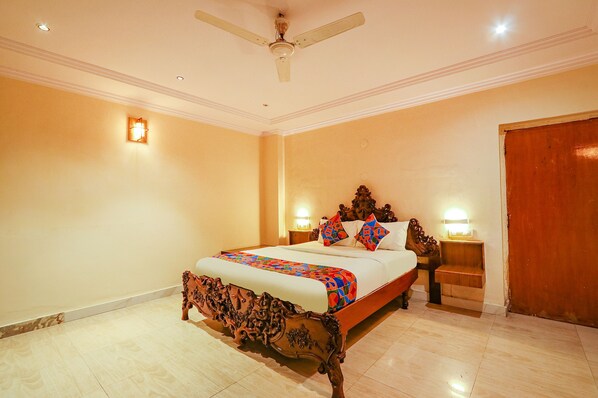 A bedroom with a wooden bed, two bedside tables with lamps, a ceiling fan, and a wooden door.