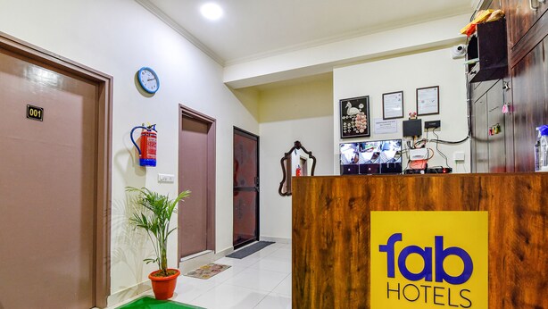 Zona de recepción de hotel con un mostrador de madera, una planta en maceta y un reloj en la pared.