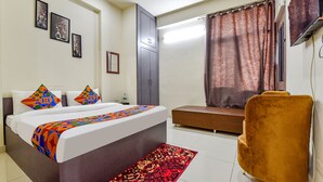 A hotel room with a bed, a bench, a chair, and a TV. - Fabhotel Moon Light Palace (Jaipur)