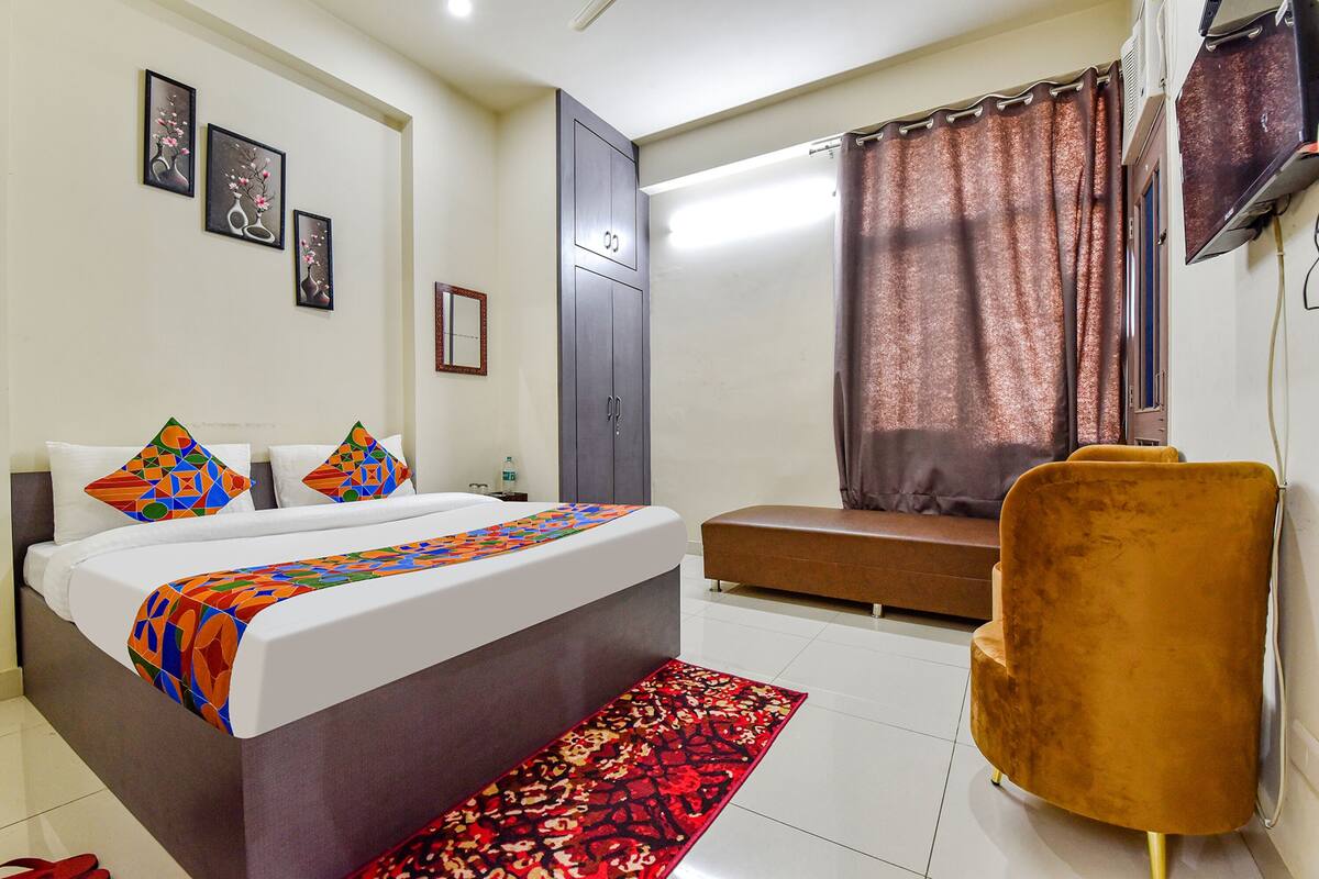 A hotel room with a bed, a bench, a chair, and a TV.
