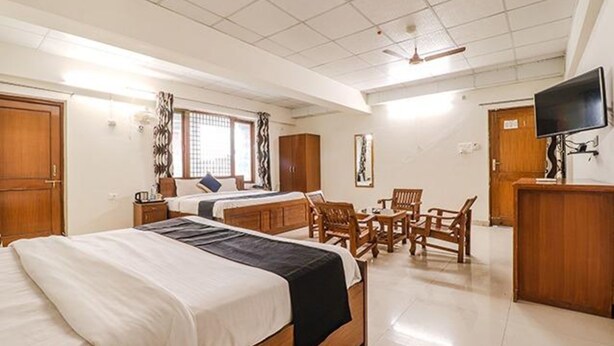 Quarto de hotel com duas camas, uma escrivaninha, uma cadeira, televisão e guarda-roupa.