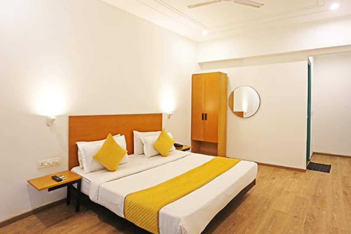 A hotel room with a large bed, a bedside table, a wardrobe, and a mirror on the wall.
