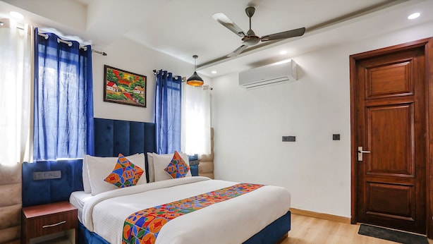 A bedroom with a bed, nightstand, and a wooden door. - FabHotel RS Golden (New Delhi)