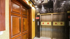 A wooden door with a glass elevator door. - FabHotel RS Golden (New Delhi)