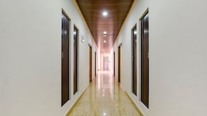 A long, narrow hallway with wooden doors on both sides and a polished marble floor. - Fabhotel Manali Heaven (Manali)