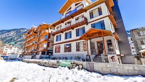 A multi-story hotel with balconies and a ski slope in the background. - Fabhotel Manali Heaven (Manali)