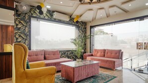 A modern living room with two sofas, a yellow armchair, and a glass coffee table. - Fabhotel Grand Inn Ii (Agra)