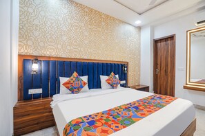 A hotel room with a bed, a wooden headboard, and a patterned wall. - Fabhotel Grand Inn Ii (Agra)